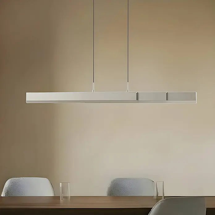 Lucande Pendelleuchte Torven - L x B x H: 121,5 x 5,5 x 8 cm, alu / grau / zink, Metall - Lineare graue Pendelleuchte über einem Holztisch.