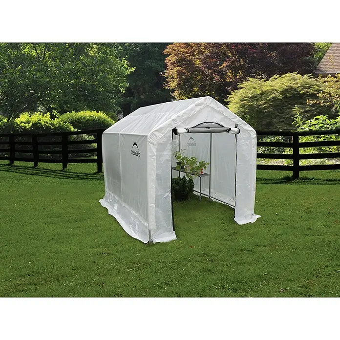 ShelterLogic Folien-Gewächshaus - 240 x 180 x 200 cm, Aluminium - Gewächshaus mit Regalen auf Rasen. Das Gewächshaus ist weiß und hat einen Reißverschluss vorne für einfachen Zugang.