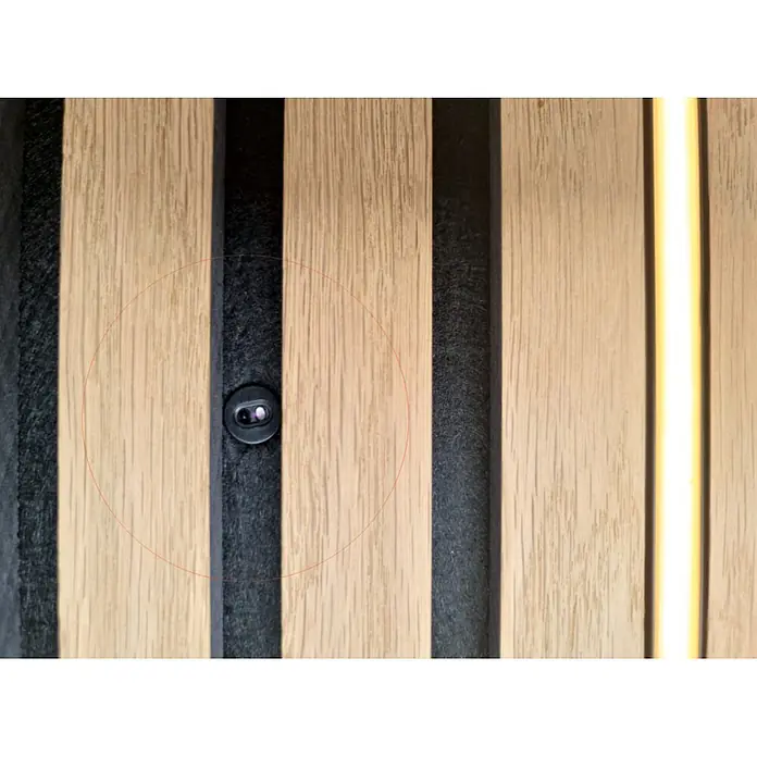 Direct Signs Sensor Akus Pir Trafo - Schwarz - Schwarzer Türspion oder Guckloch in heller Holzlamellenwand mit dunklem Akustikfilz und vertikalem Lichtstreifen.