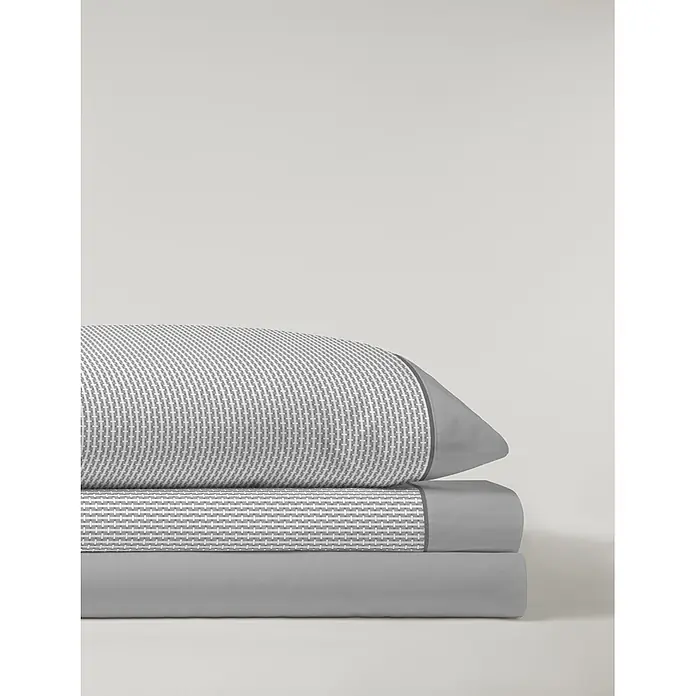 Juego de sábanas Serena Iker - L x An: 190 x 135 cm, 50 % Algodón - 50 % Poliéster, Gris, 3 pzs. - Pila de ropa de cama plegada: almohada/nórdico con estampado geométrico gris y blanco, y sábanas grises lisas.