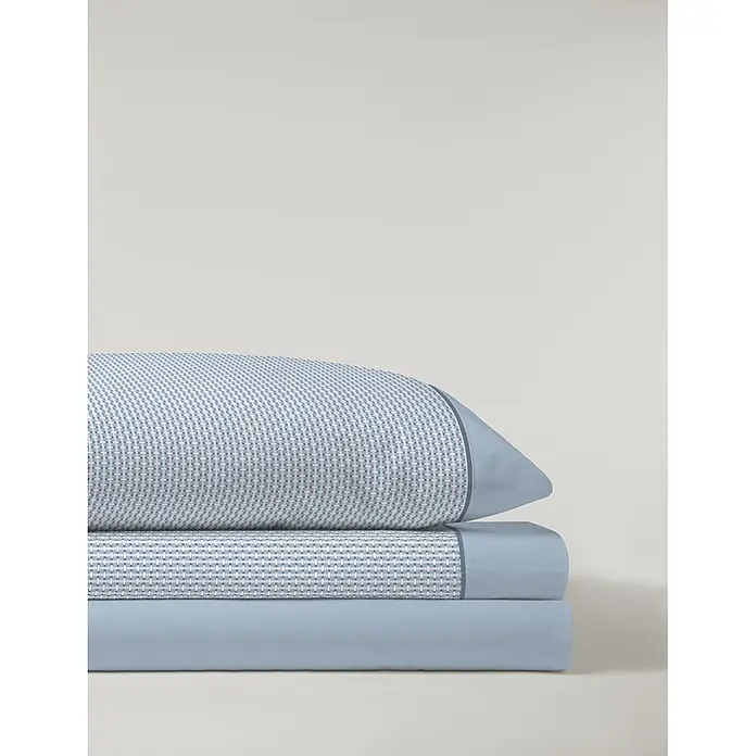 Juego de sábanas Serena Iker - L x An: 190 x 150 cm, 50 % Algodón - 50 % Poliéster, Azul, 4 pzs. - Una pila de ropa de cama azul y blanca con estampado, que incluye una almohada y dos sábanas dobladas, una azul claro lisa.