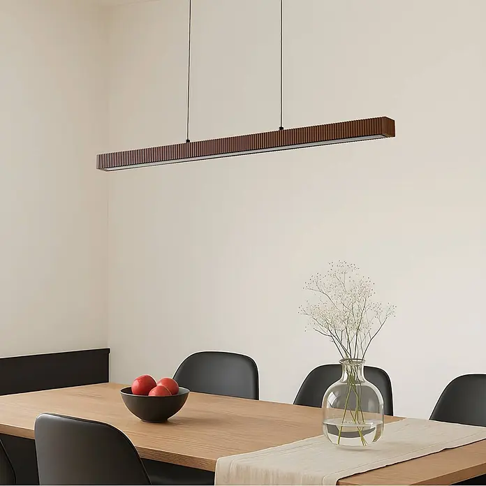 Lucande Pendelleuchte Emara - L x B x H: 115 x 10 x 5 cm, Holz dunkel, eiche dunkel, Schwarz, weiß - Braune Latten-Linear-Pendelleuchte über einem Esstisch aus Holz mit schwarzen Stühlen.
