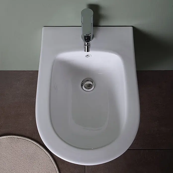 Kiamami Valentina Wand-WC-Kombination - Spülrandlos, WC Abgang: Senkrecht, Weiß - Weißes Keramik-Bidet mit modernem Chrom-Wasserhahn und Abfluss, von oben gesehen.