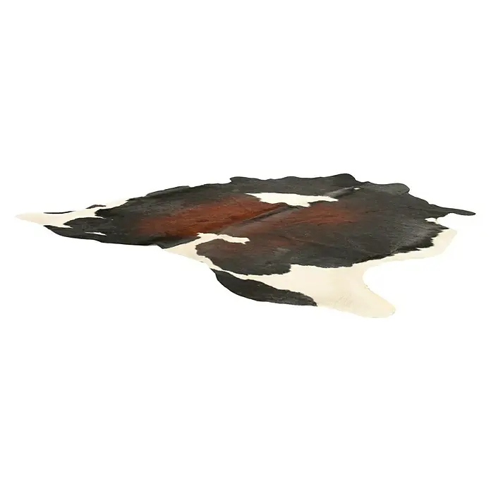 Esbeco Alfombra de piel de vaca - Exótico oscuro, 100% piel auténtica - Se muestra una piel de vaca marrón y blanca en el suelo. El llamativo patrón y la forma natural la convierten en una pieza llamativa.
