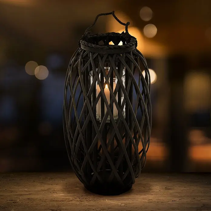 ECD Germany Deko-Tischleuchte Laterne Ried mit Henkel Rattan Windlicht mit Glaseinsatz Kerzenständer - L x B x H: 28 x 28 x 50 cm - Dunkle Weidenlaterne mit brennender Kerze im Glashalter auf Holzoberfläche für warme Atmosphäre.