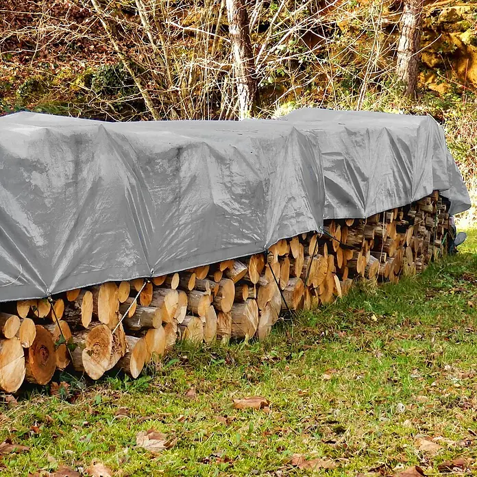 ECD Germany Abdeckplane Gartenplane 260g/m² mit Ösen Reißfeste Regenplane Polyethylen - 260 g/m², Kunststoff - Graue Schutzplane deckt einen großen Stapel Brennholz im Freien ab.