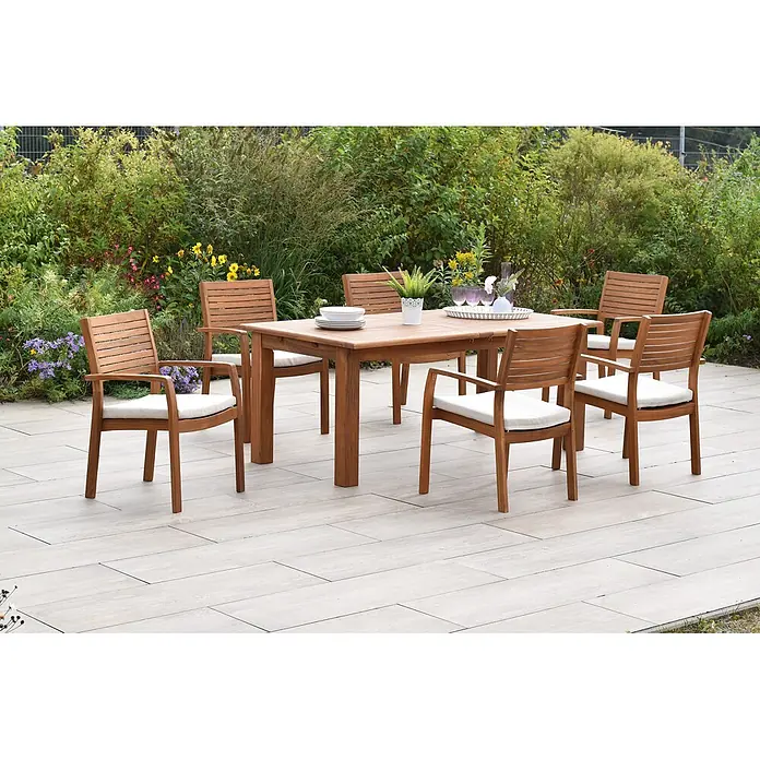 Merxx Gartentisch-Set Batavia - Gesamtumfang: 13 -tlg., L x B x H: 260 x 100 x 75 cm, Akazie, Stapelbar - Hölzerne Garten-Essgruppe mit rechteckigem Tisch und sechs Stühlen mit hellen Auflagen auf einer Terrasse.