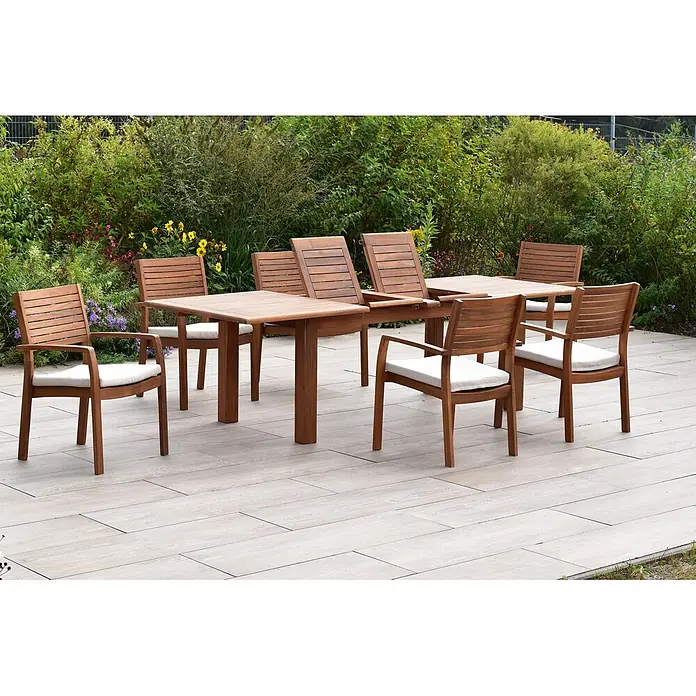 Merxx Gartentisch-Set Batavia - Gesamtumfang: 13 -tlg., L x B x H: 260 x 100 x 75 cm, Akazie, Stapelbar - Hölzerne Outdoor-Essgruppe mit acht Stühlen und einem Tisch auf einer Terrasse, umgeben von einem Garten.