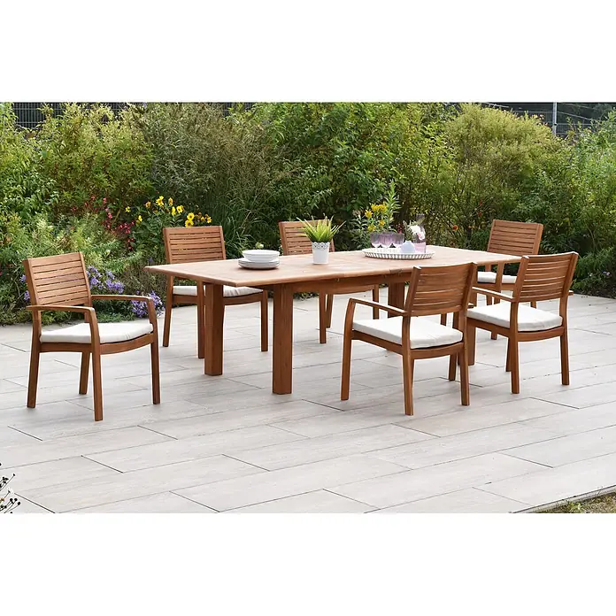 Merxx Gartentisch-Set Batavia - Gesamtumfang: 13 -tlg., L x B x H: 260 x 100 x 75 cm, Akazie, Stapelbar - Hölzerne Outdoor-Essgruppe mit rechteckigem Tisch und sechs Stühlen mit cremefarbenen Auflagen, auf einer Terrasse.
