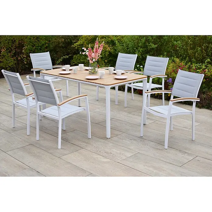 Merxx Gartentisch-Set Pisa - Gesamtumfang: 7 -tlg., Aluminium/Textil, Stapelbar - Eine Outdoor-Essgruppe mit einem hellen Holztisch und weißen Stühlen mit hellgrauem Stoff und Holzarmlehnen auf einer Terrasse.