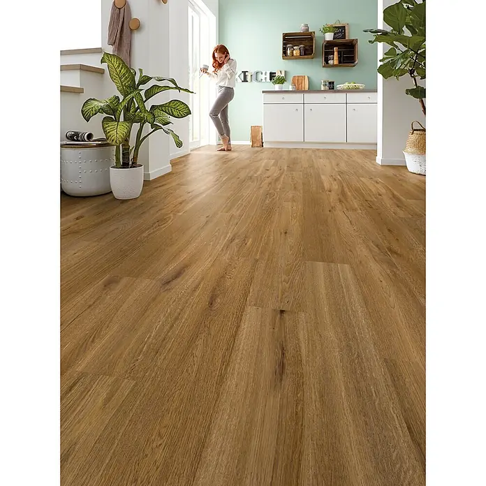Decolife Designboden Naturestyle Pure - Oak Amber, Landhausdiele, 1.220 x 185 x 9 mm - Naturgetreue Holzoptik-Bodenplanken in einem hellen Raum, auf denen eine Frau barfuß steht.