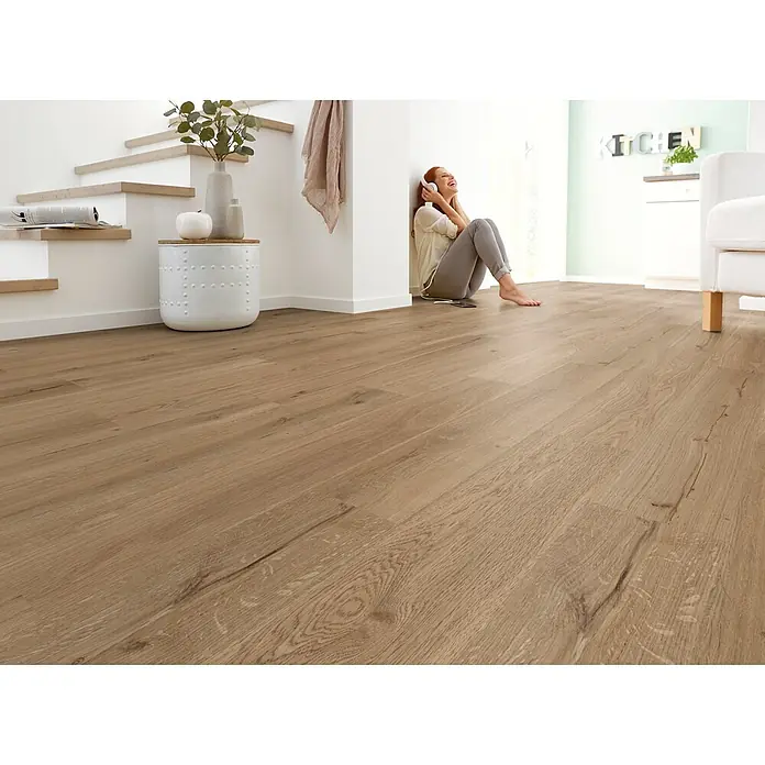 Decolife Designboden Naturestyle Pure - Oak Smoke, Landhausdiele, 1.220 x 185 x 9 mm - Hellbrauner Holzplankenfussboden in einem modernen Zuhause, auf dem eine Person bequem sitzt.