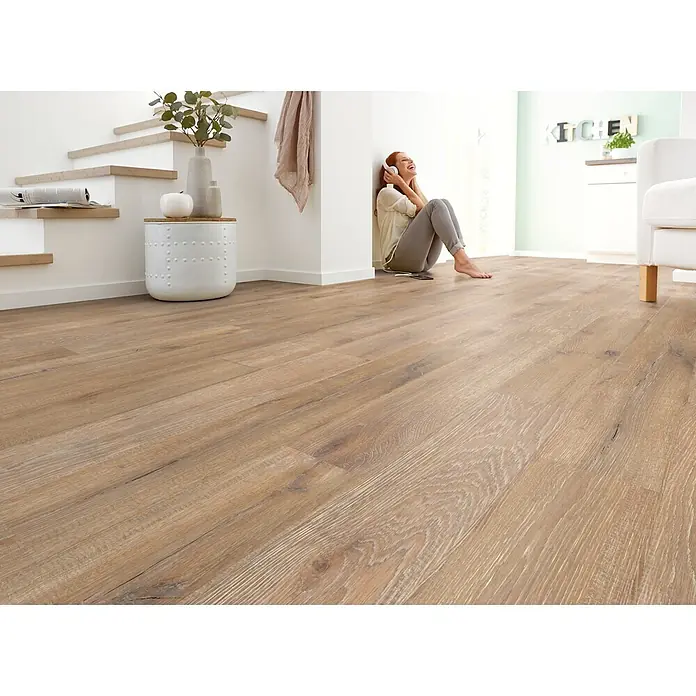 Decolife Designboden Naturestyle Pure - Oak Raw, Landhausdiele, 1.220 x 185 x 9 mm - Heller Holz-Dielenboden mit natürlicher Maserung, gezeigt in einem modernen Wohnbereich mit entspannender Person.