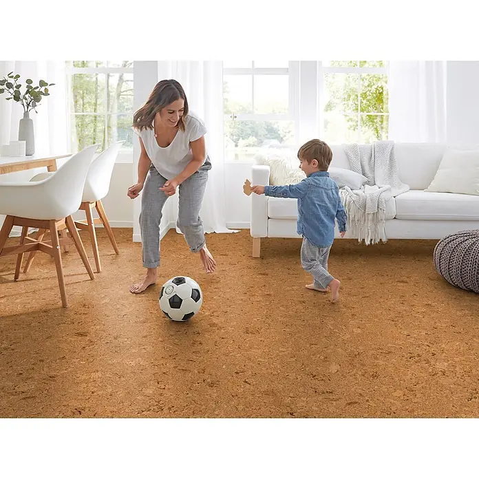 Corklife Studiostyle Korkboden - Evora, 905 x 295 x 10,5 mm - Natürlicher Korkboden in einem Wohnzimmer, auf dem eine Mutter und ein Kind barfuß Fußball spielen.