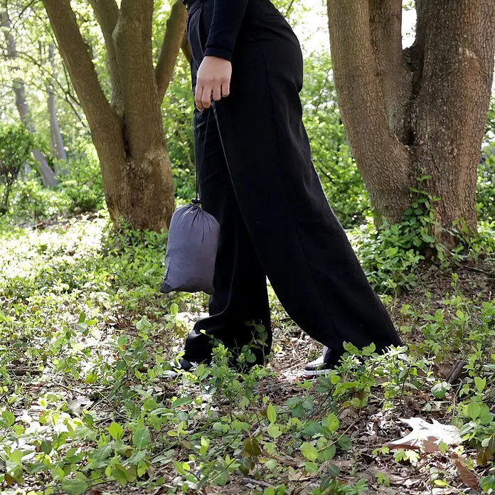 SVITA Hängematte - L x B: 270 x 140 cm, Sonstiges, Grau - Grauer Stoffbeutel mit Kordelzug, von einer Person im Wald getragen, Betonung der Tragbarkeit.