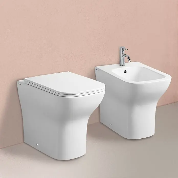 Kiamami Valentina Stand-WC-Kombination - Spülrandlos, WC Abgang: Senkrecht, Weiß - Modernes weißes Keramik-WC und Bidet, nebeneinander in einer Badezimmereinrichtung.
