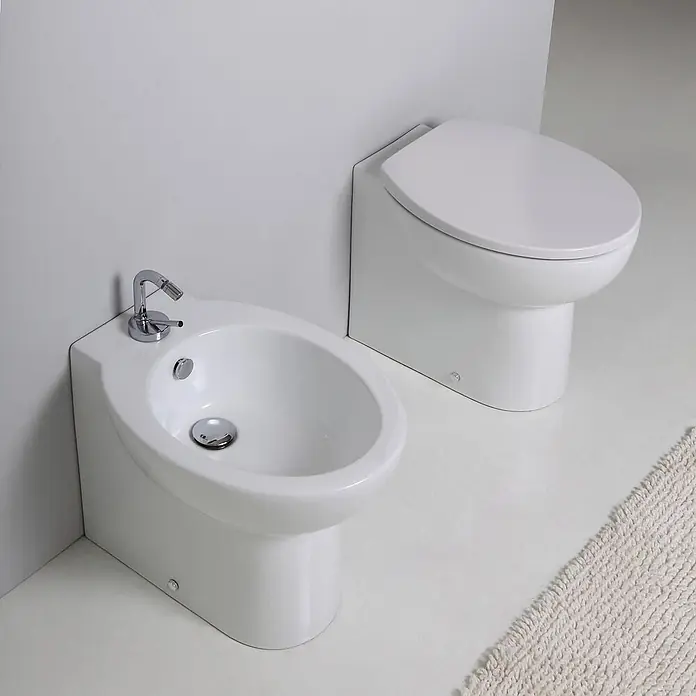 Kiamami Valentina Stand-WC-Kombination - Mit Spülrand, WC Abgang: Senkrecht, Weiß - Weißes Keramik-Bidet mit Chromarmatur und passendes WC. Beide sind bodenstehend.