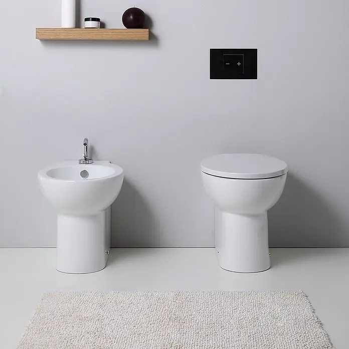 Kiamami Valentina Stand-WC-Kombination - Mit Spülrand, WC Abgang: Senkrecht, Weiß - Weißes Keramik-Standbidet mit Chromarmatur und passender Toilette in einem modernen Badezimmer.