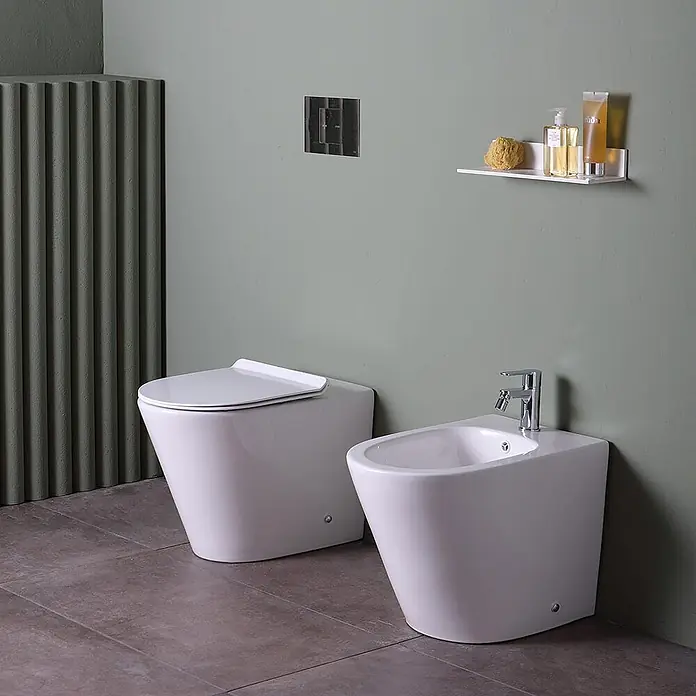 Kiamami Valentina Stand-WC-Kombination - Spülrandlos, WC Abgang: Senkrecht, Weiß - Modernes weißes Keramik-WC und Bidet in einem zeitgenössischen Badezimmer mit minimalistischem Design und Chromarmaturen.