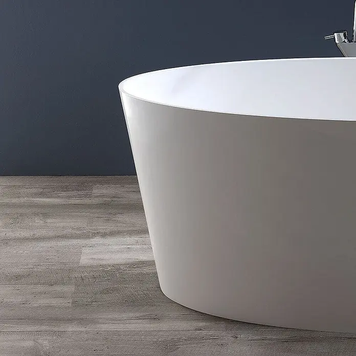 Kiamami Valentina Freistehende Badewanne - L x B: 1.580 x 718 cm, ABS-Kunststoff und Acryl, Weiß - Moderne weiße freistehende Badewanne in einem Badezimmer mit dunkelblauer Wand und hellem Holzfußboden. Ein Chromwasserhahn ist sichtbar.