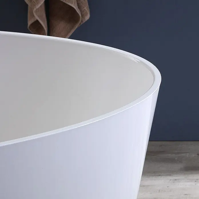 Kiamami Valentina Freistehende Badewanne - L x B: 1.580 x 718 cm, ABS-Kunststoff und Acryl, Weiß - Nahaufnahme einer weißen, freistehenden Badewanne mit glatter Oberfläche, in einem Badezimmer mit dunkler Wand und Holzfußboden.
