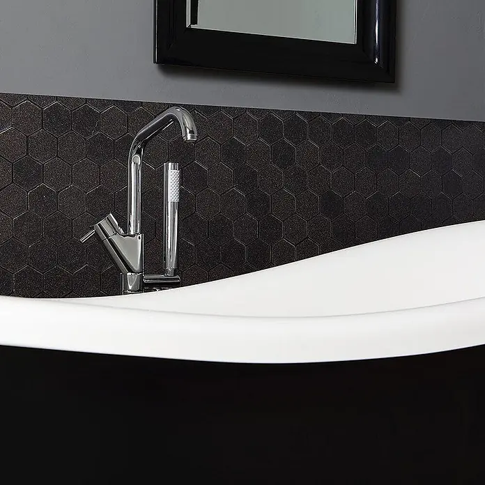 Kiamami Valentina Freistehende Badewanne - L x B: 1.670 x 752 cm, ABS-Kunststoff und Acryl, Schwarz - Chrom-Badewannenarmatur mit Handbrause, montiert an einer freistehenden weiß-schwarzen Badewanne mit dunklem Fliesenspiegel.