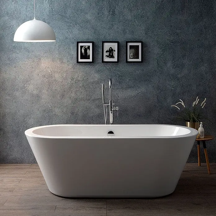 Kiamami Valentina Freistehende Badewanne - L x B: 1.700 x 750 cm, ABS-Kunststoff und Acryl, Weiß - Weiße freistehende Badewanne in einem modernen Badezimmer mit Standarmatur und Beistelltisch mit Pflanze und Seife.
