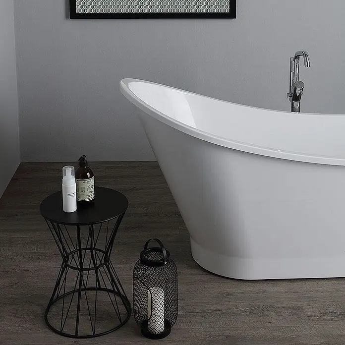Kiamami Valentina Freistehende Badewanne - L x B: 1.590 x 490 cm, ABS-Kunststoff und Acryl, Weiß - Weiße freistehende Badewanne in modernem Bad, mit schwarzem Beistelltisch mit Pflegeprodukten und Laterne auf Holzfußboden.