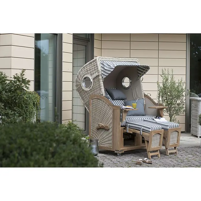 Mr. Deko Strandstuhl Strandkorb Düne Bullauge Teak PE Shell Dessin 545 - Teakholz. Polyrattan, Rückenlehne verstellbar, PE Shell, B x T x H: 125 x 80 x 170 cm - Outdoor-Strandkorb aus Korbgeflecht mit gestreiften Kissen und Holzrahmen auf einer Terrasse, bereit zur Entspannung.