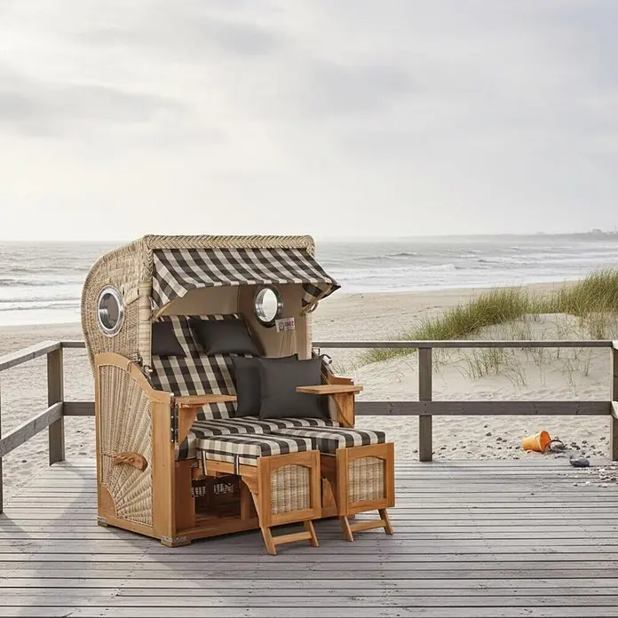 Mr. Deko Strandstuhl Strandkorb Düne - Teakholz. Polyrattan, Rückenlehne verstellbar, PE Shell, B x T x H: 125 x 80 x 170 cm - Strandkorb aus Korbgeflecht und Holz mit schwarz-beige karierten Polstern und dunklen Kissen auf einer Holzterrasse am Strand.