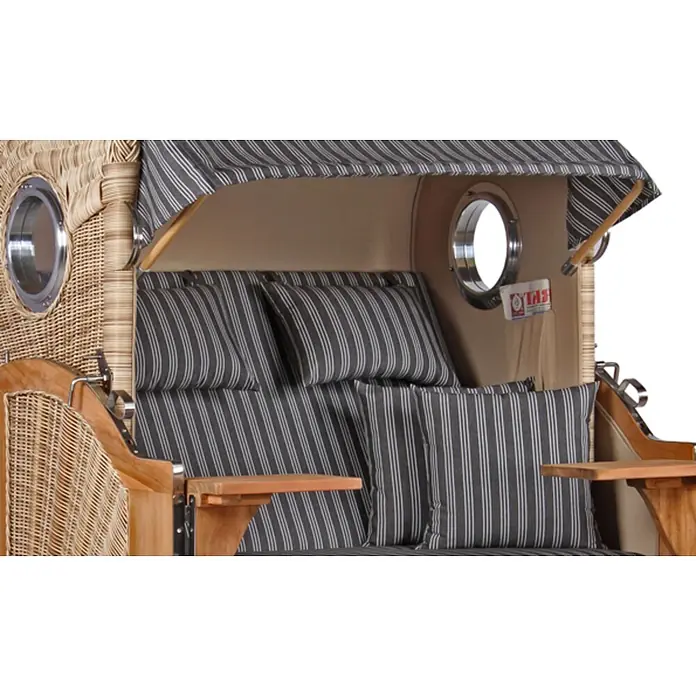 Mr. Deko Strandstuhl Strandkorb Düne Bullauge Teak PE Shell Dessin 500 - Teakholz. Polyrattan, Rückenlehne verstellbar, PE Shell, B x T x H: 125 x 80 x 170 cm - Innenansicht eines Strandkorbs aus Korbgeflecht mit grau-weiß gestreiften Kissen, Holztischen und Bullaugenfenstern.