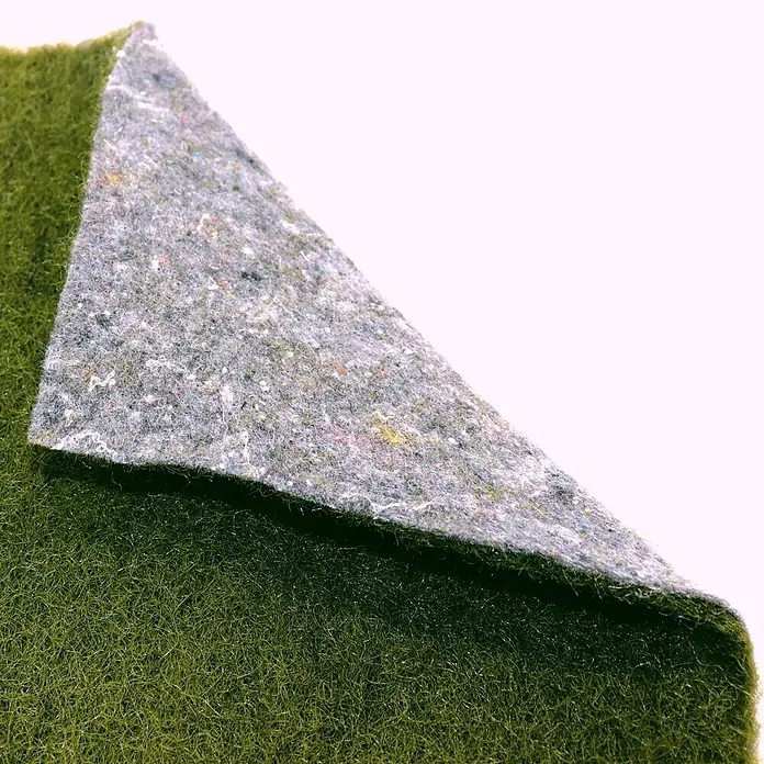 Aquagart Bodenschutzvlies 18m x 0,75m grün Ufermatte Böschungsmatte -  - Grüner Kunstrasenteppich mit hochgeklappter Ecke, die grauen Filzrücken zeigt.