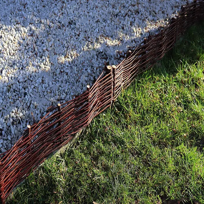 Aquagart Steckzaun-Element 8 30x60cm Beeteinfassungen aus Weide I - braun, Holz - Geflochtene Weidenumrandung in Braun, die Kiesweg und grünes Gras trennt.