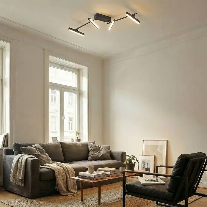 Lindby Deckenstrahler Eldrin - schwarz, schwarz - Schwarze Deckenleuchte mit vier verstellbaren LED-Stäben, beleuchtet ein modernes Wohnzimmer.
