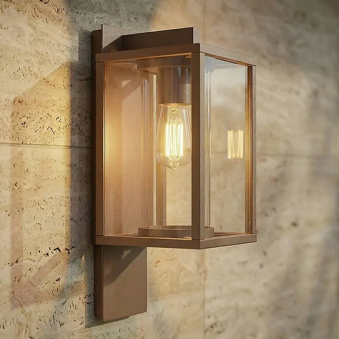 Lucande Wandleuchte aussen in braun, Aussenlampe Wand -  - Rechteckige bronzefarbene Außenwandleuchte mit Glaspaneelen und sichtbarer Glühbirne, an strukturierter Steinwand montiert.