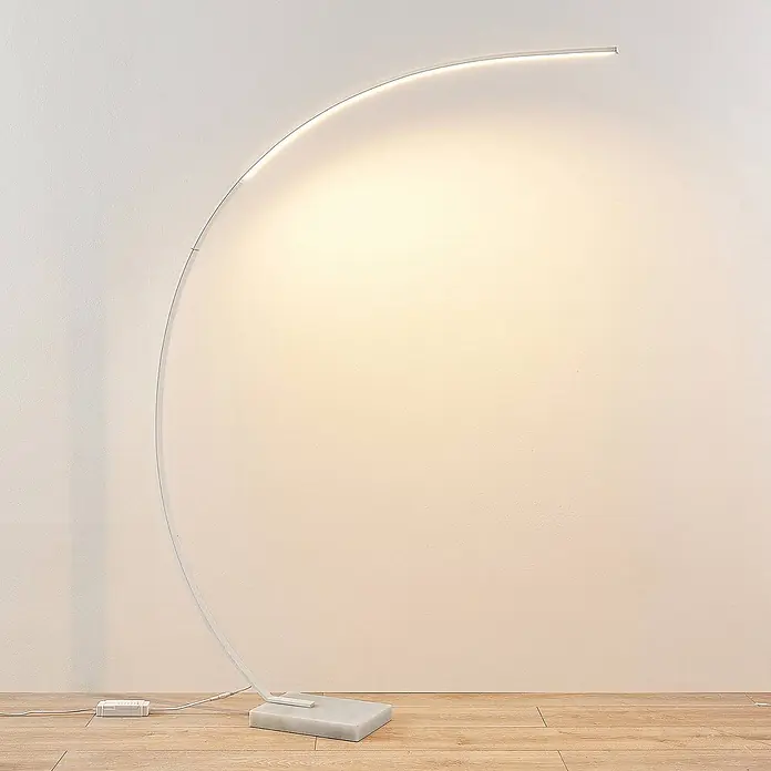 Lindby Stehleuchte Kendra - Höhe: 180 cm, weiß / opal, weiß / opal - Eine moderne weiße Bogen-LED-Stehleuchte mit Marmorsockel, die eine Wand beleuchtet.
