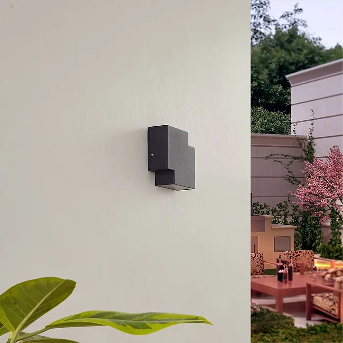 Lindby Außenwandleuchte Fendir - schwarz, IP54 - Schwarze, geometrische Außenwandleuchte an einer hellen Wand, beleuchtet eine Terrasse.