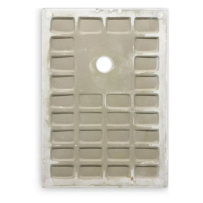 Kiamami Valentina Duschwanne - L x B: 1.600 x 800 cm, Verbundwerkstoff, Weiß - Rückseite einer hellgrauen Fliese mit rechteckigen Vertiefungen und mittigem Loch für bessere Haftung.
