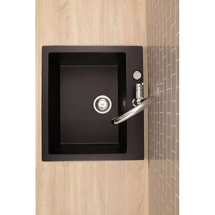 Respekta Einbauspüle Oakville - 60 x 53 cm, Verbundwerkstoff, Schwarz - Schwarzes Spülbecken mit Chromarmatur und Abfluss in heller Holztheke, neben beigen Metrofliesen.