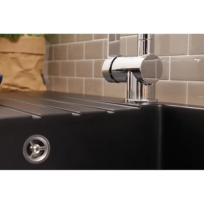 Respekta Einbauspüle Almonto - 86 x 50 cm, Verbundwerkstoff, Schwarz - Nahaufnahme einer modernen schwarzen Küchenspüle mit einem eleganten Chromwasserhahn, mit geripptem Abtropfbereich und rundem Abfluss.