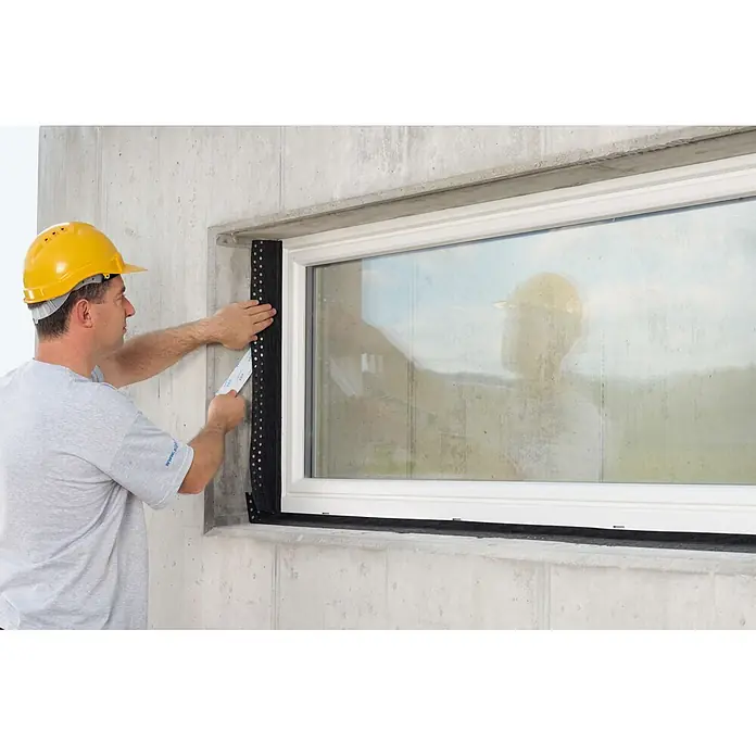 Siga Klebeband Fentrim 2 - 25 m x 100 mm, Außen, Schwarz - Ein Bauarbeiter montiert eine schwarze Dichtungsbahn mit Noppen an einem Fensterrahmen, um die Fensterabdichtung zu verbessern.