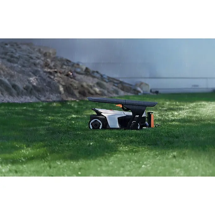 Segway Mähroboter-Garage X - L x B x H: 755 x 670 x 227 mm, Segway Mähroboter-Modelle Navimow X420E, X430E und X450E - Weiß-schwarzer Mähroboter mit orangefarbenem Akzent auf grünem Gras im Regen.