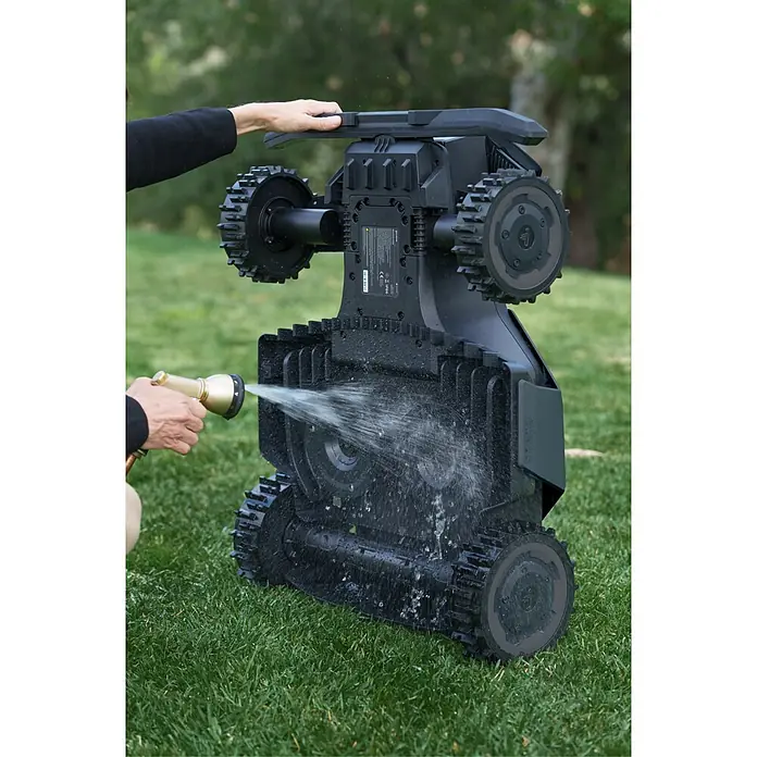 Segway Mähroboter Navimow X450 - 5.000 m², Schnittbreite: 43 cm, Satellitengestützte Navigation, RTK - Schwarzer Mähroboter mit Raupenantrieb wird von Person mit Schlauch gereinigt. Unterseite wird mit Wasser besprüht.