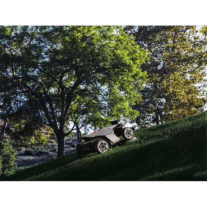 Segway Mähroboter Navimow X450 - 5.000 m², Schnittbreite: 43 cm, Satellitengestützte Navigation, RTK - Ein dunkelgrauer Rasenroboter mit robusten Rädern fährt eine steile Rasenfläche im Freien hinauf. Er demonstriert seine Fähigkeit in unebenem Gelände.