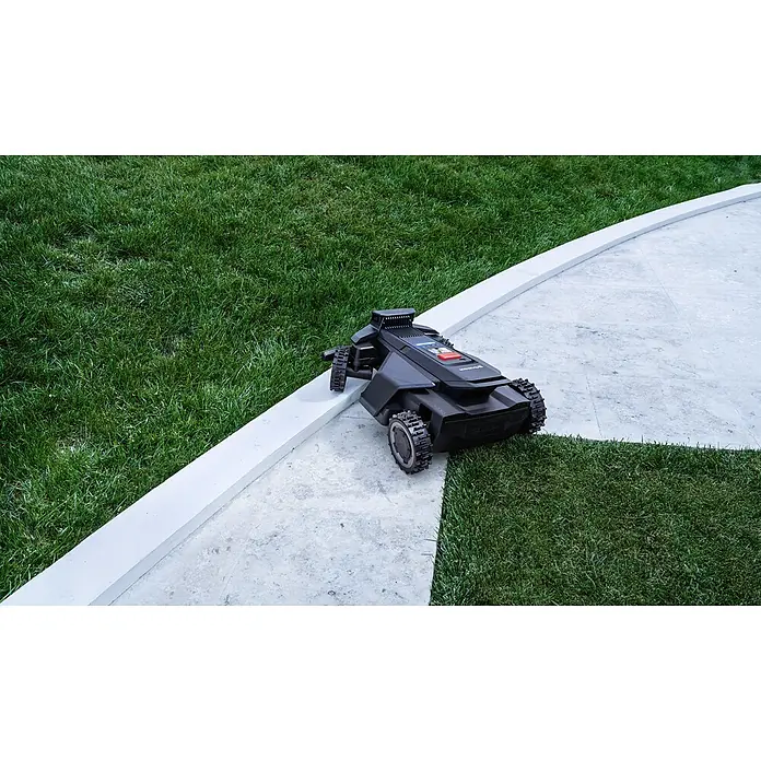 Segway Mähroboter Navimow X450 - 5.000 m², Schnittbreite: 43 cm, Satellitengestützte Navigation, RTK - Schwarzer Rasenroboter mit Ketten auf einem Betonweg neben grünem Gras.