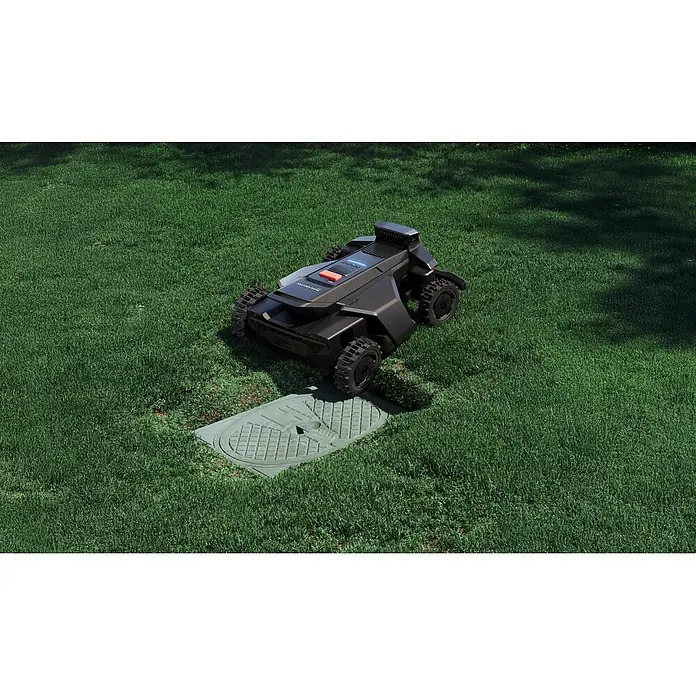 Segway Mähroboter Navimow X450 - 5.000 m², Schnittbreite: 43 cm, Satellitengestützte Navigation, RTK - Dunkelgrauer Rasenroboter mit robusten Rädern auf einem Rasen, neben einem grünen Versorgungsschachtdeckel.