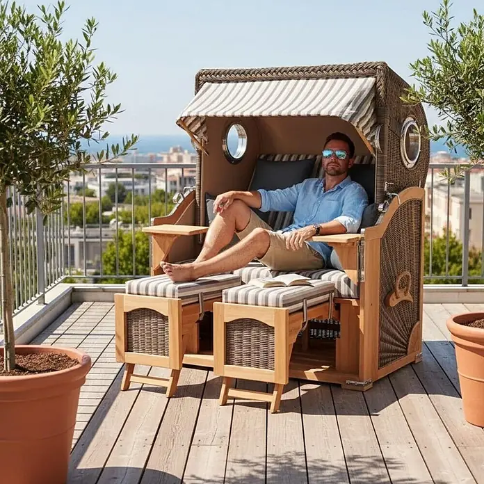 Mr. Deko Strandstuhl Strandkorb Düne Bullauge Teak PE Grey Dessin 545 - 1 Stk., Teakholz. Polyrattan, Rückenlehne verstellbar, PE Grey - Mann entspannt in einem Strandkorb aus Holz und Geflecht mit gestreiftem Verdeck und Kissen auf einem sonnigen Balkon.