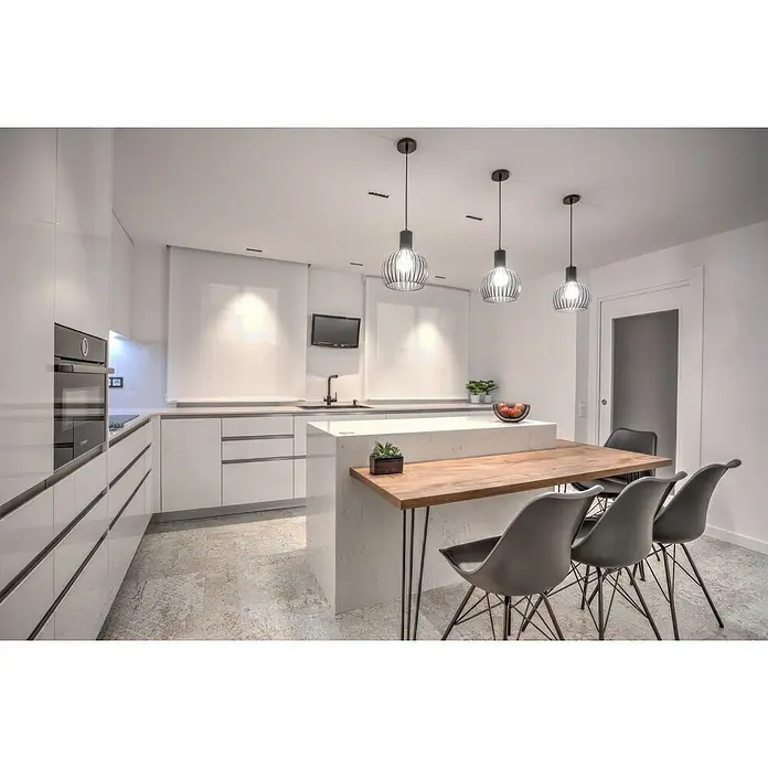 Feinsteinzeugfliese Carpet Natural - 59,2 x 59,2 cm, Sand, Matt - Elegante weiße Küche mit einer Insel, die einen integrierten Holzesstisch und schwarze Stühle umfasst.