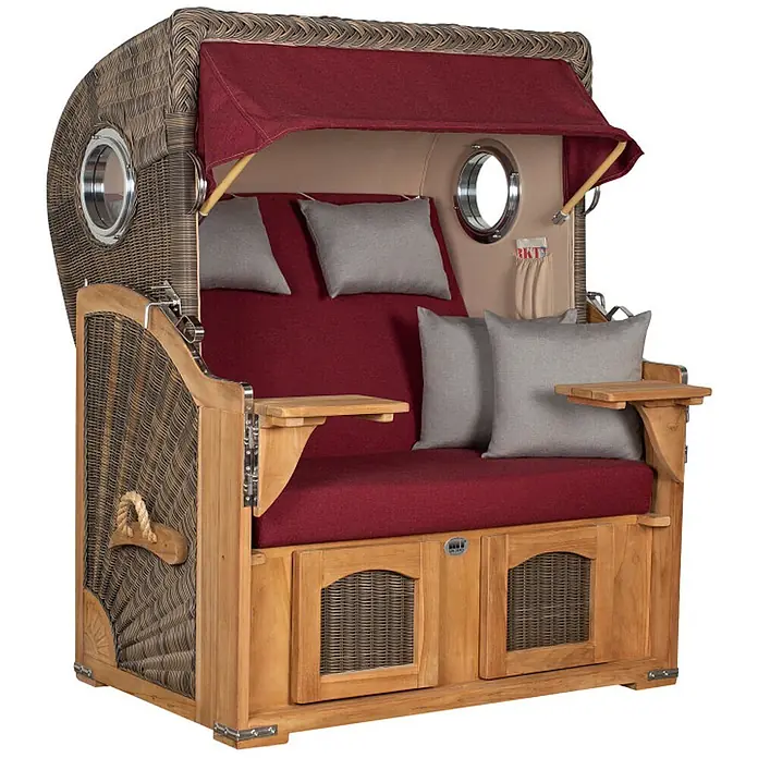 Mr. Deko Strandstuhl Strandkorb Düne Bullauge Teak PE Grey Dessin 594 - 1 Stk., Teakholz. Polyrattan, Rückenlehne verstellbar, PE Grey - Ein luxuriöser Strandkorb aus Holz und Geflecht mit roten Polstern, grauen Kissen, Bullaugen und ausklappbaren Beistelltischen.