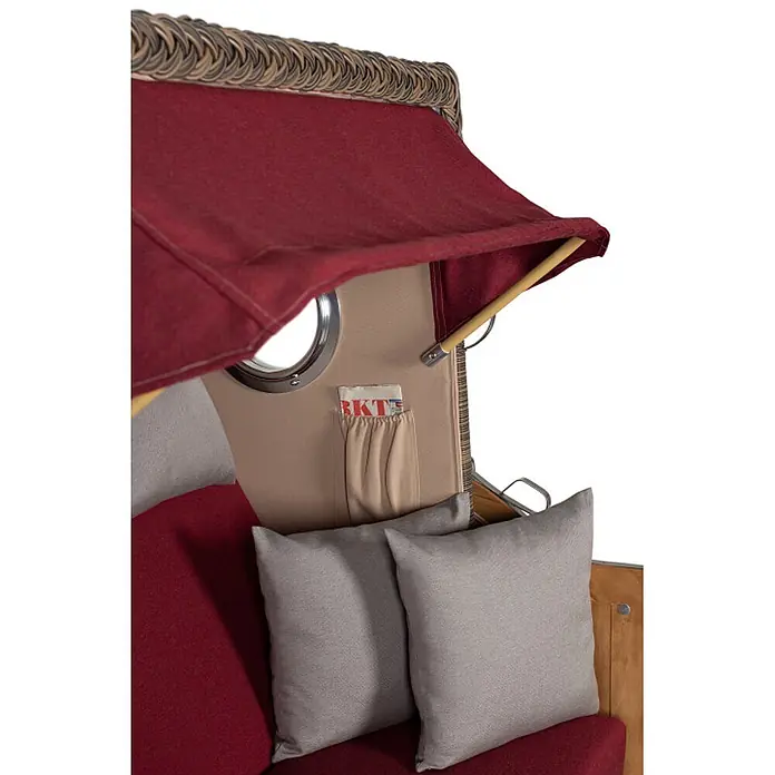 Mr. Deko Strandstuhl Strandkorb Düne Bullauge Teak PE Grey Dessin 594 - 1 Stk., Teakholz. Polyrattan, Rückenlehne verstellbar, PE Grey - Innenansicht eines Strandkorbs mit rotem Stoff, beigen Seiten, Bullauge, Magazintasche und grauen Kissen.